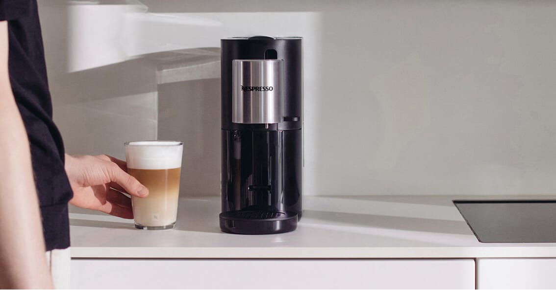 Máquina Nespresso Atelier y persona bebiendo café