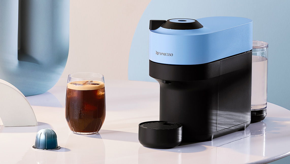 Máquina vertuo de color azul junto a taza de café helado