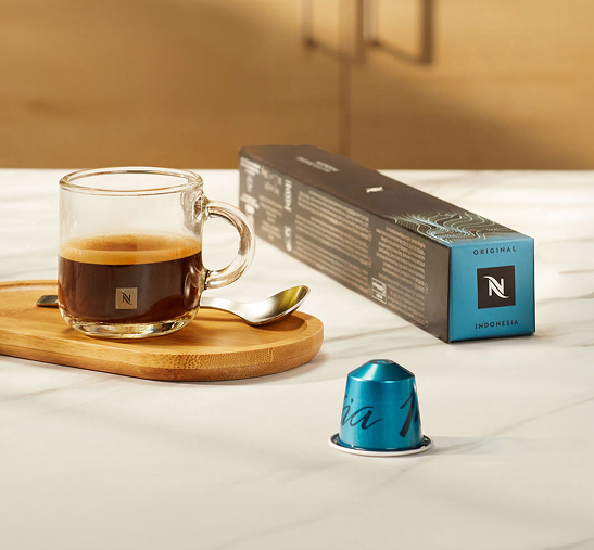 Cápsulas de color azul junto a taza transparente