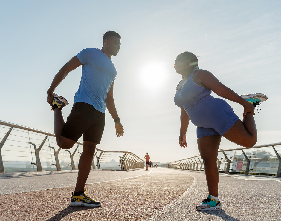 Dos deportistas estirando antes de correr