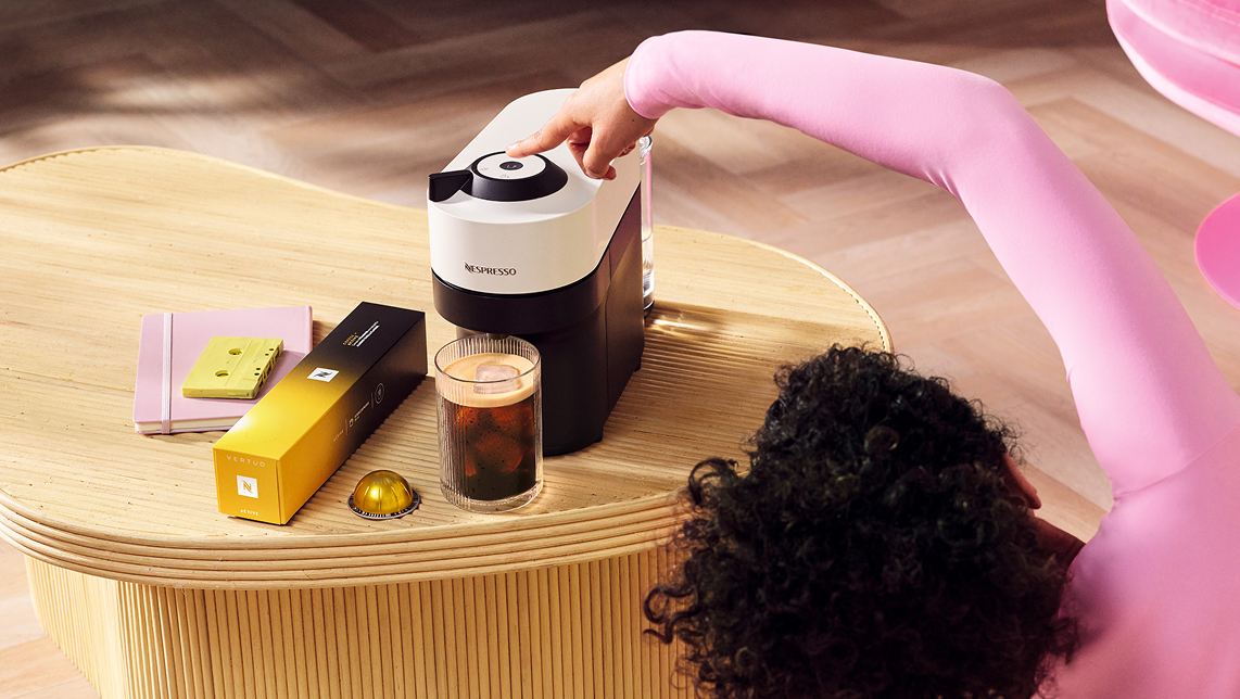 Mujer estirando junto a cafetera de color blanco