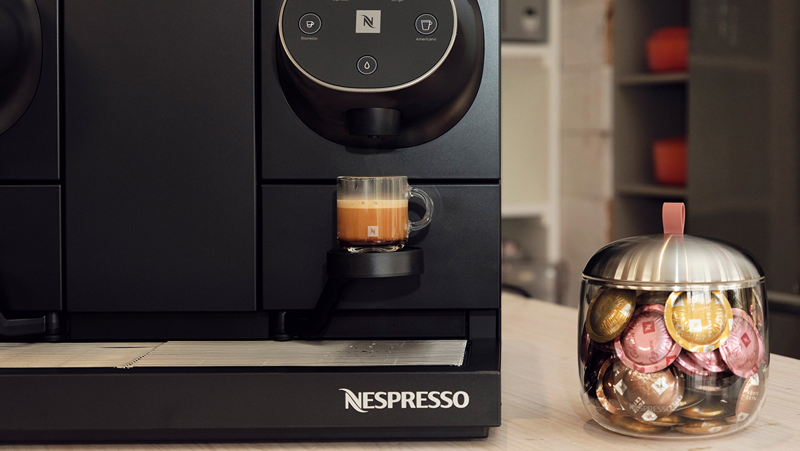 Cafetera Nespresso junto a un contenedor de cápsulas de cristal.