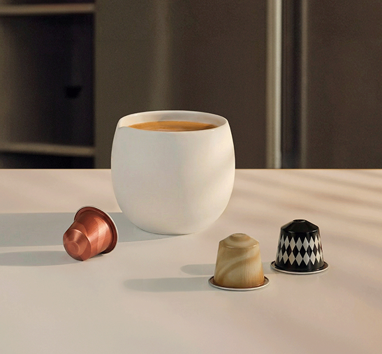 Taza de café junto a cápsulas del sistema Original alrededor.