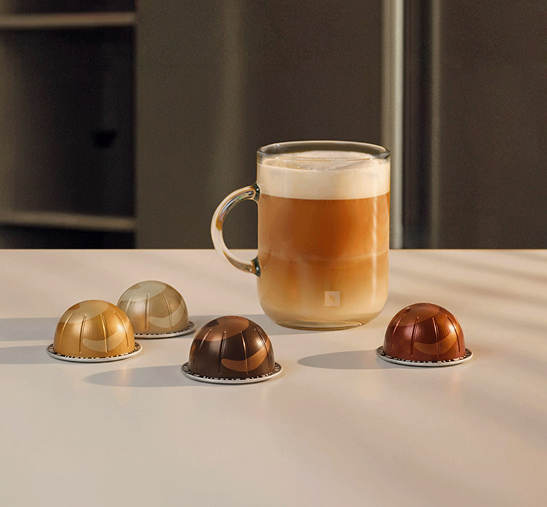 Vaso de cristal con café junto a cápsulas Vertuo.