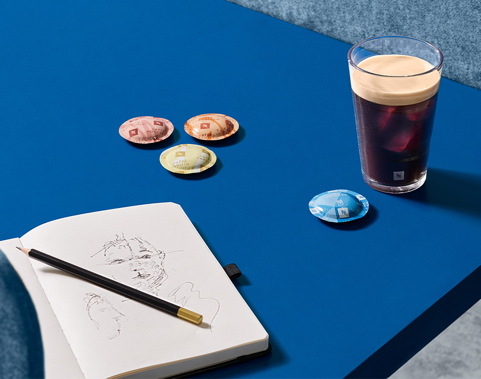 Vaso de café junto a cápsulas Nespresso en una mesa azul