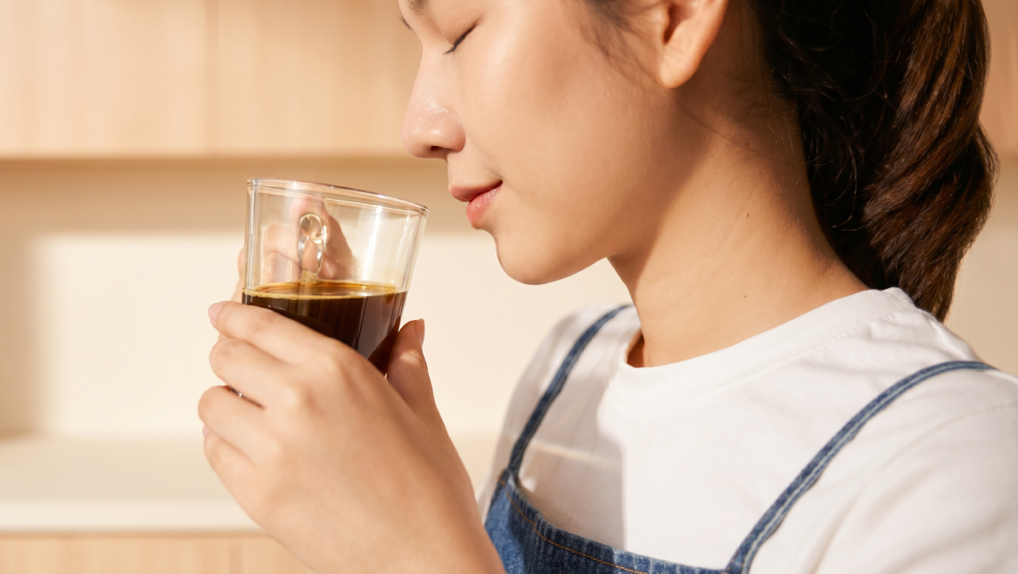 Mujer disfrutando del aroma del café.