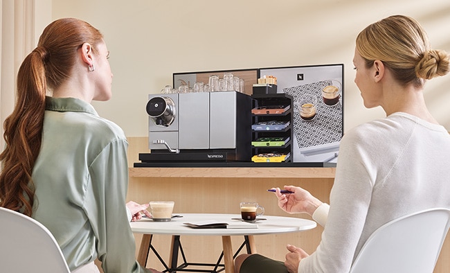 Two women sitting at table with Nespresso Professional coffee