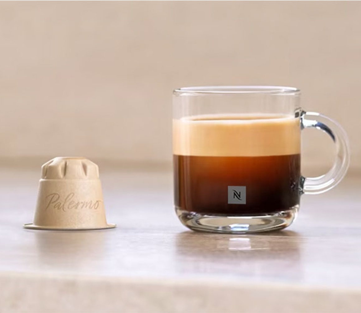 Ein Werbebanner mit einer Kaffeetasse auf einem Keramiktisch und einer Kaffeekapsel. 