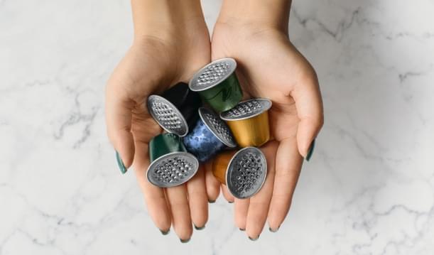 Imagem de cápsulas de café Nespresso usadas sobre as mãos de uma pessoa